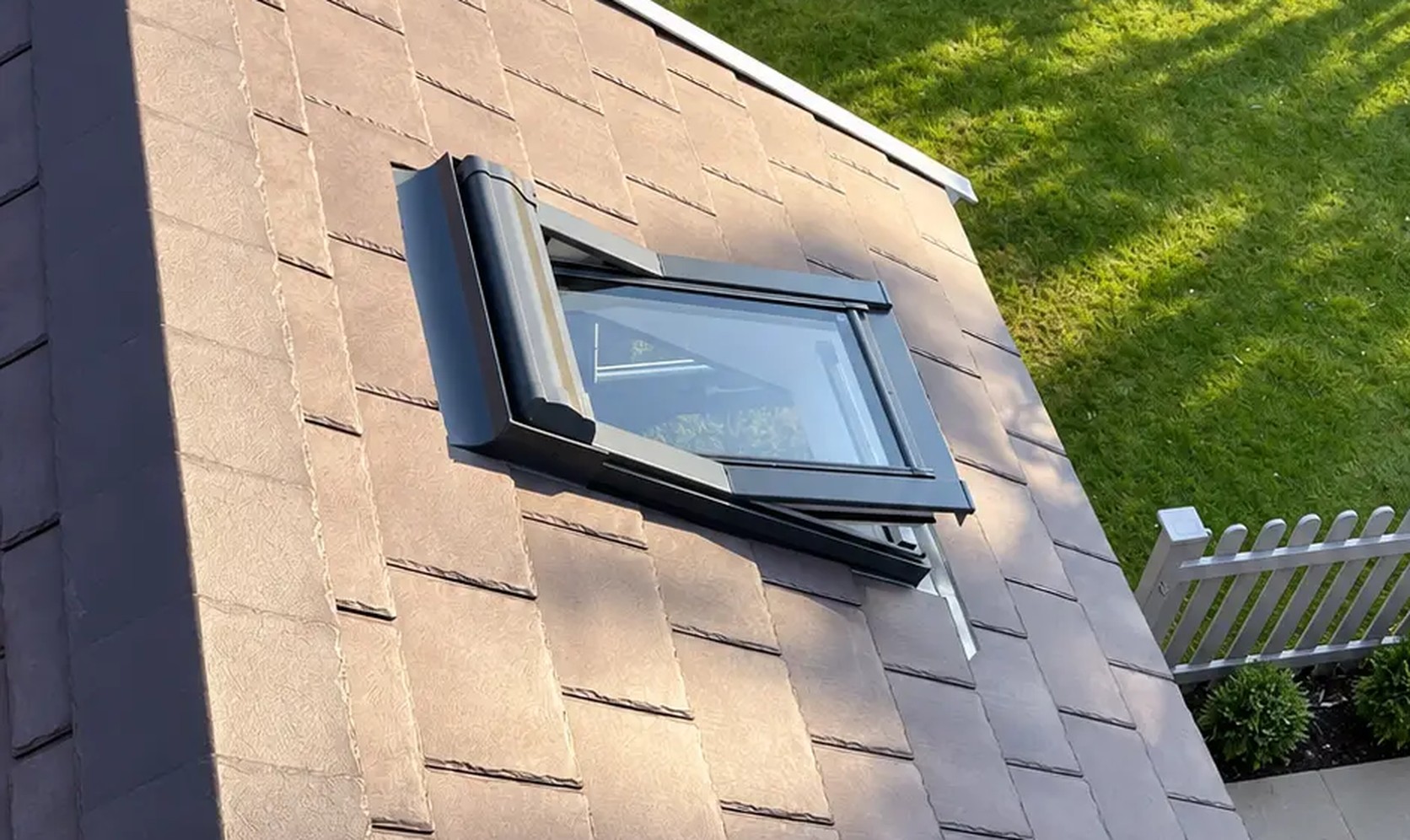 Two open roof windows set into a brown tiled pitched roof, seen from above